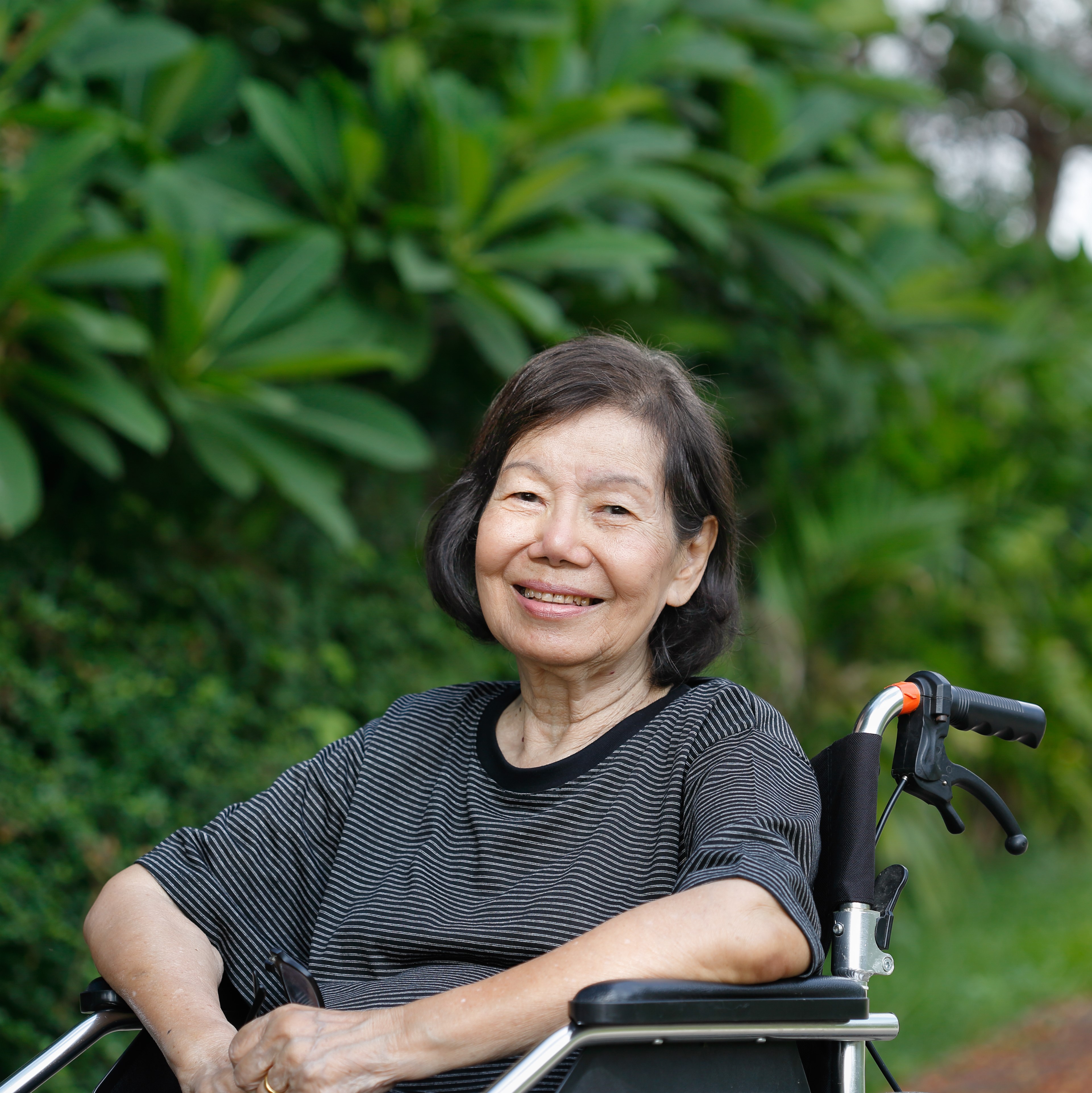 Elderly woman in a wheelchair smiling at the camera. 